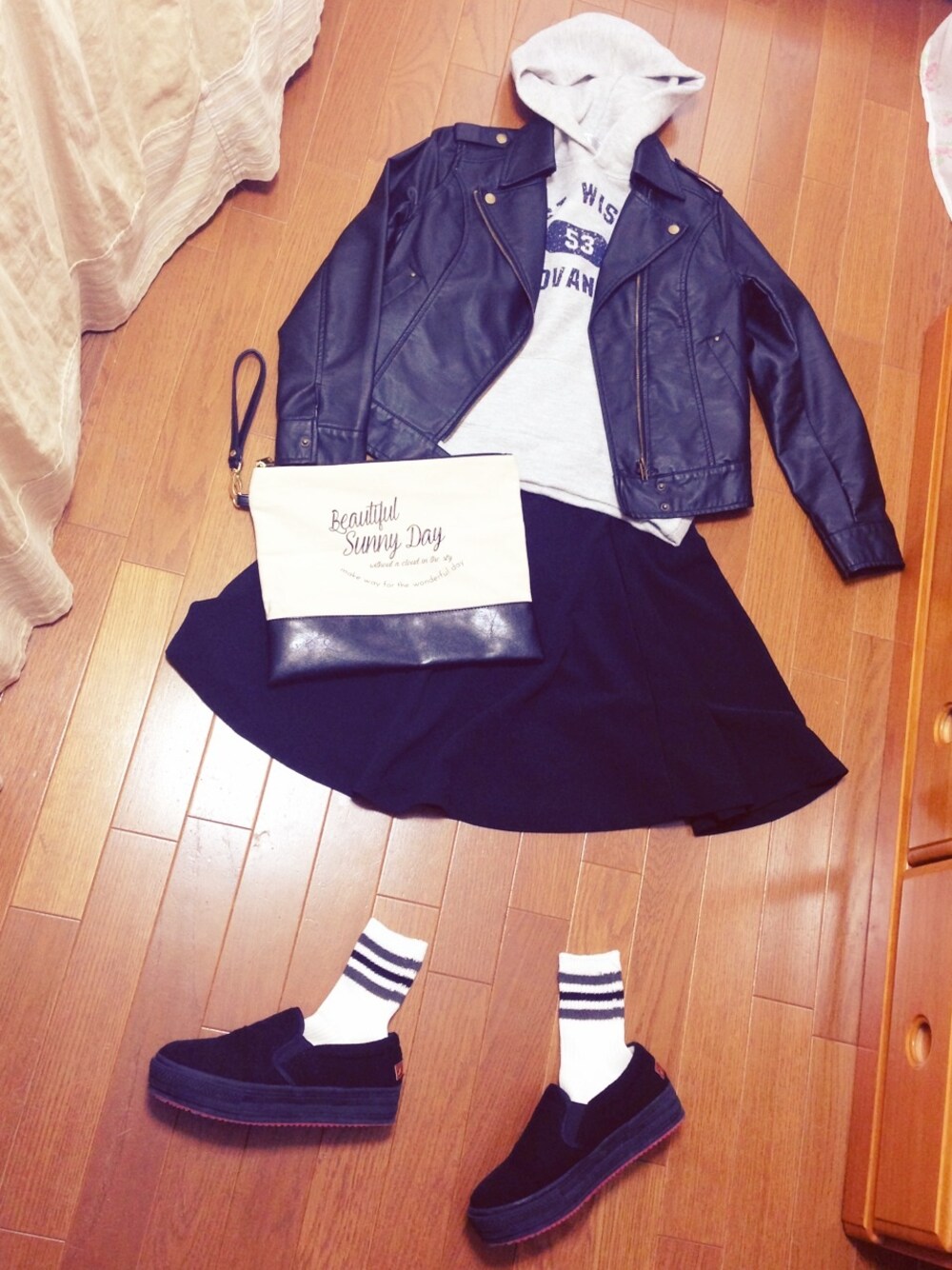 ブラック系のライダースジャケット、グレー系のパーカー、ブラック系のスカートを着用したレディースの春コーディネートの1枚目の写真