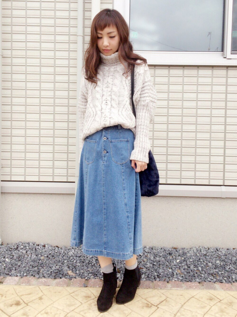 グレー系のニット/セーター、ブルー系のデニムスカート、ブルー系のショルダーバッグを着用したレディースの秋コーディネートの1枚目の写真