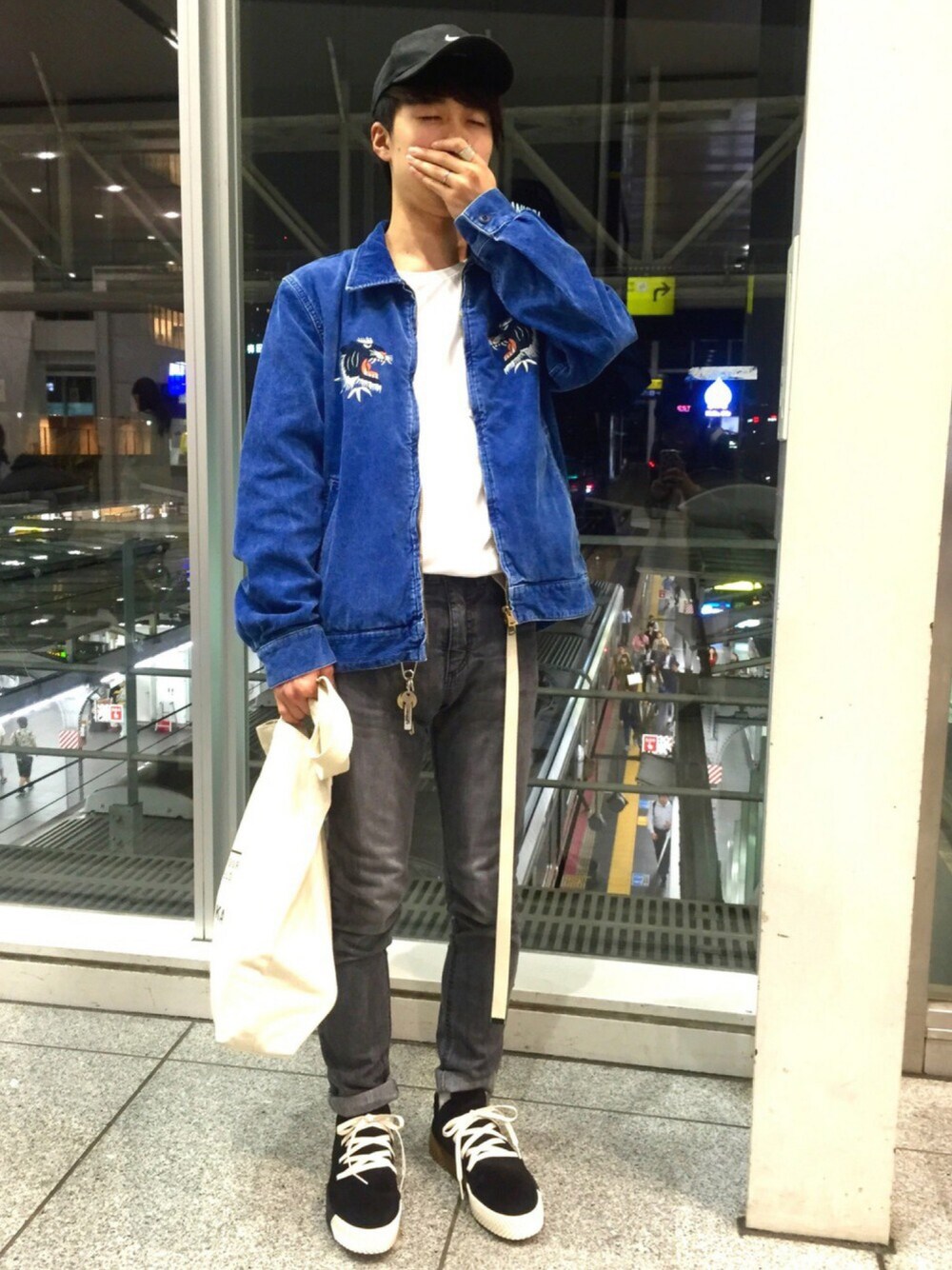 ブラック系のデニムパンツ、ホワイト系のトートバッグ、ブラック系のスニーカーを着用したメンズの秋コーディネートの1枚目の写真