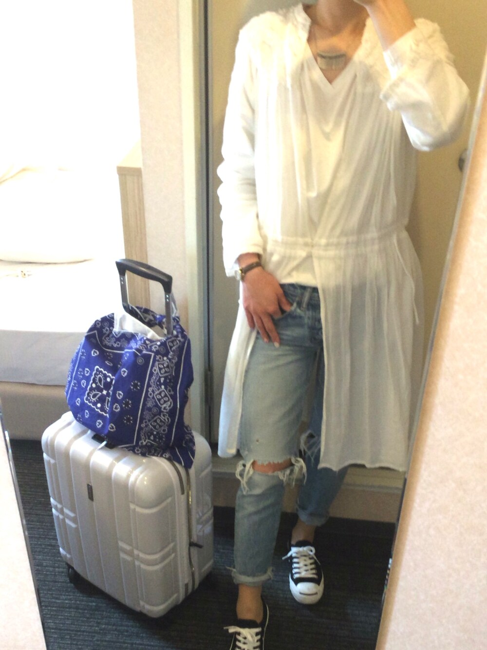 ブルー系のデニムパンツ、ホワイト系のシャツワンピース、ブラック系のスニーカーを着用したレディースの春コーディネートの1枚目の写真