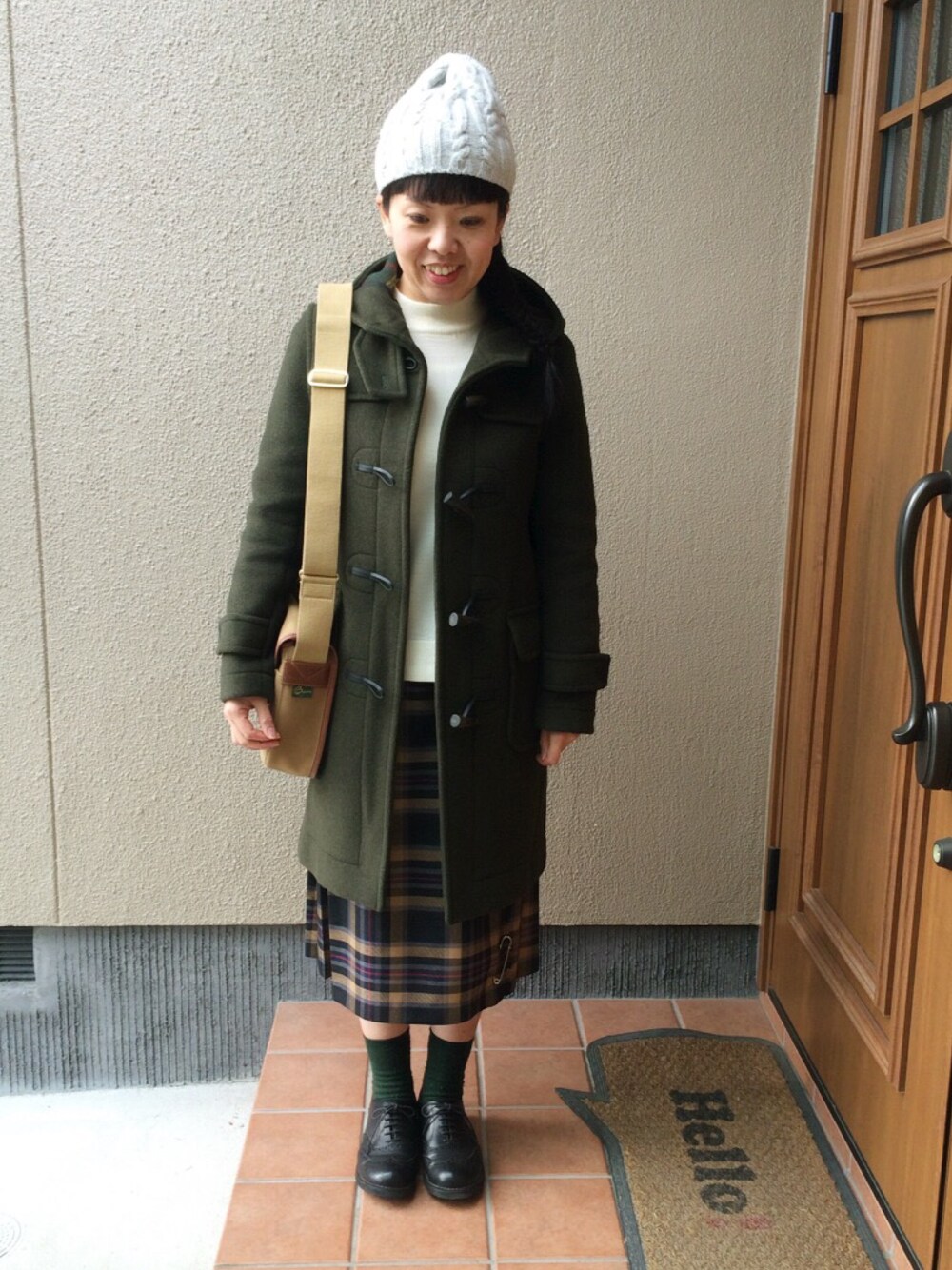 グリーン系のダッフルコート、グリーン系のショルダーバッグ、ブルー系のスカートを着用したレディースの冬コーディネートの1枚目の写真