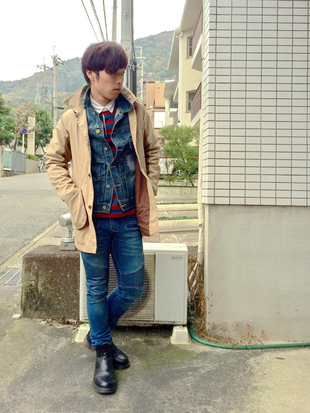 ブラック系のブーツ、レッド系のTシャツ/カットソー、ベージュ系のトレンチコートを着用したメンズの秋コーディネートの1枚目の写真