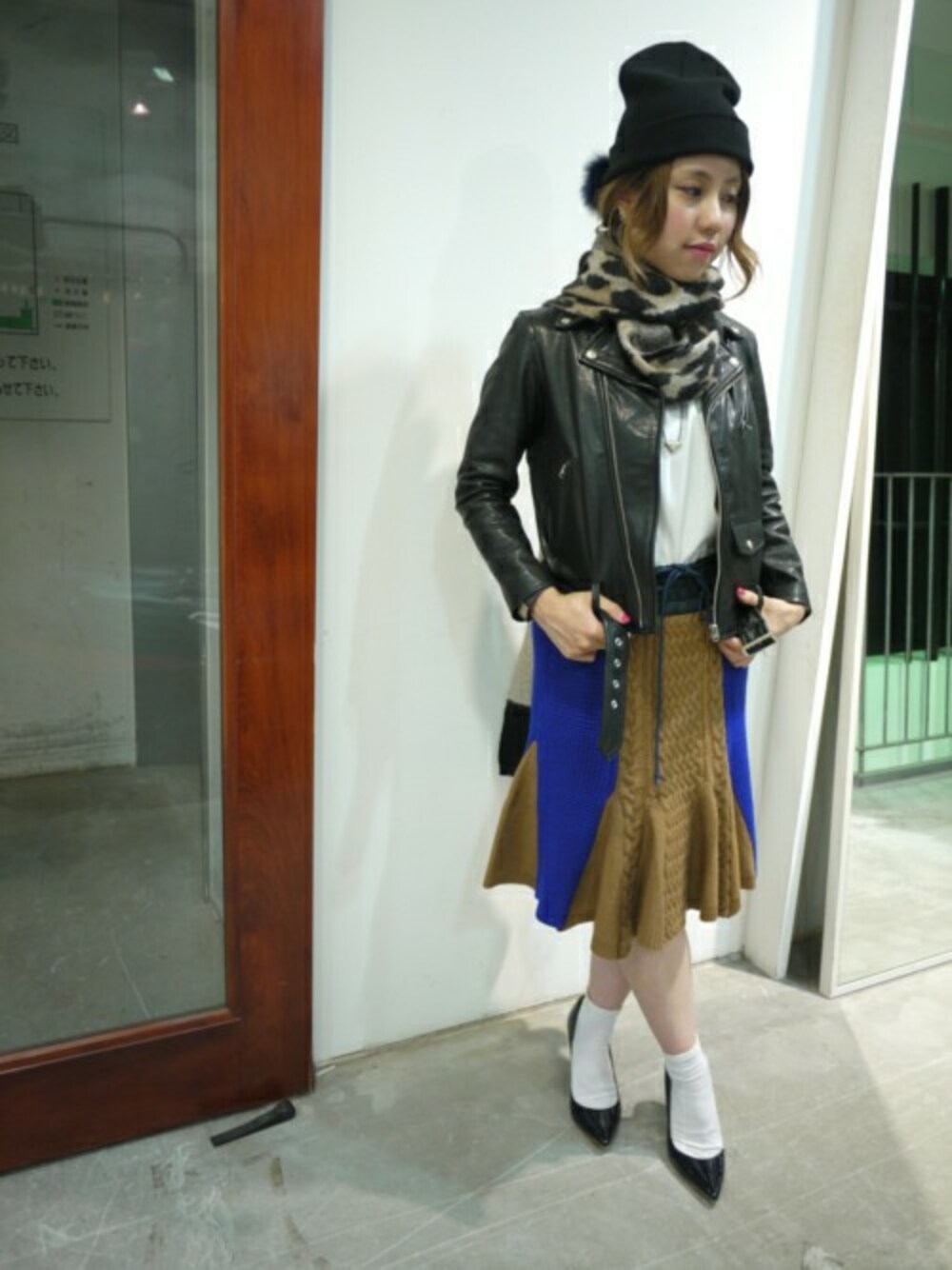 ブラック系のパンプス、ベージュ系のスカート、ブラック系のライダースジャケットを着用したレディースの秋コーディネートの1枚目の写真