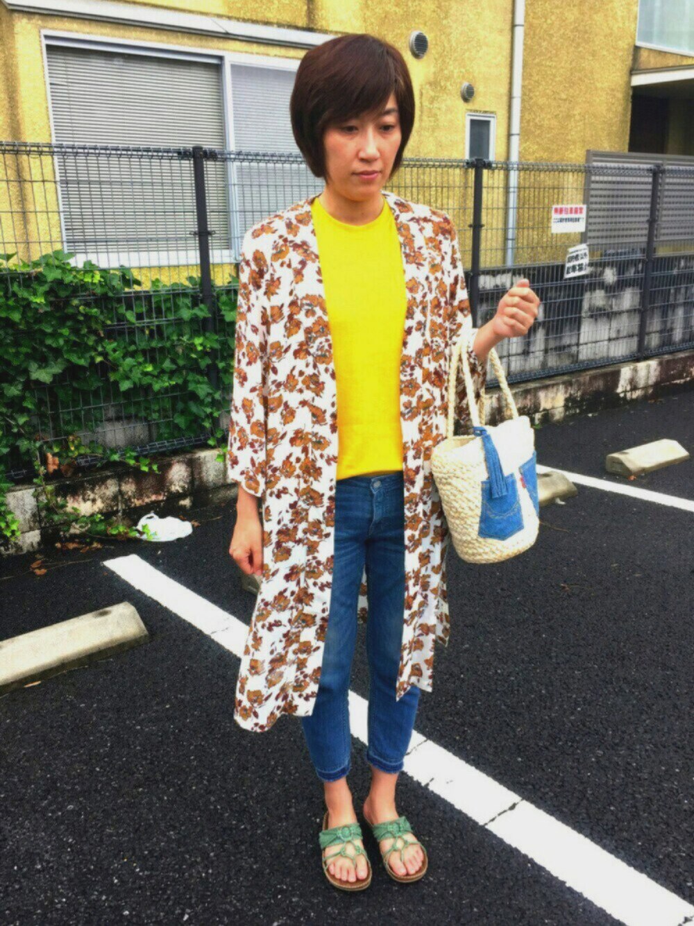 イエロー系のタンクトップ、ホワイト系のカーディガン/ボレロ、ブルー系のサンダルを着用したレディースの夏コーディネートの1枚目の写真