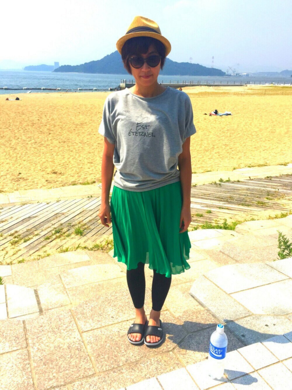 グレー系のTシャツ/カットソー、グリーン系のスカート、ブラック系のサンダルを着用したレディースの秋コーディネートの1枚目の写真