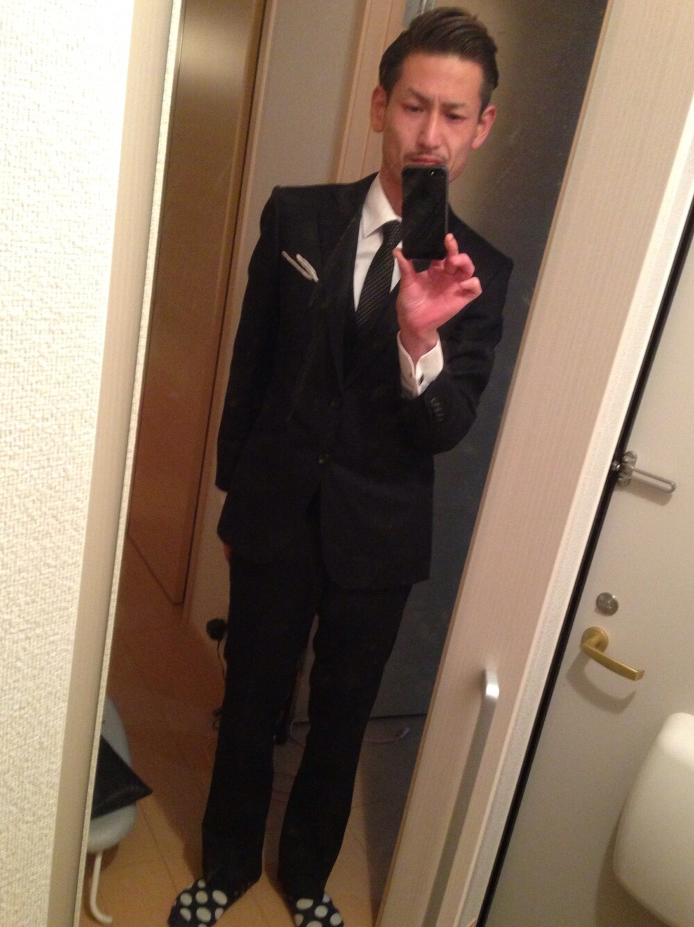 ブルー系のスーツジャケット、ブラック系のネクタイを着用したメンズの春コーディネートの1枚目の写真