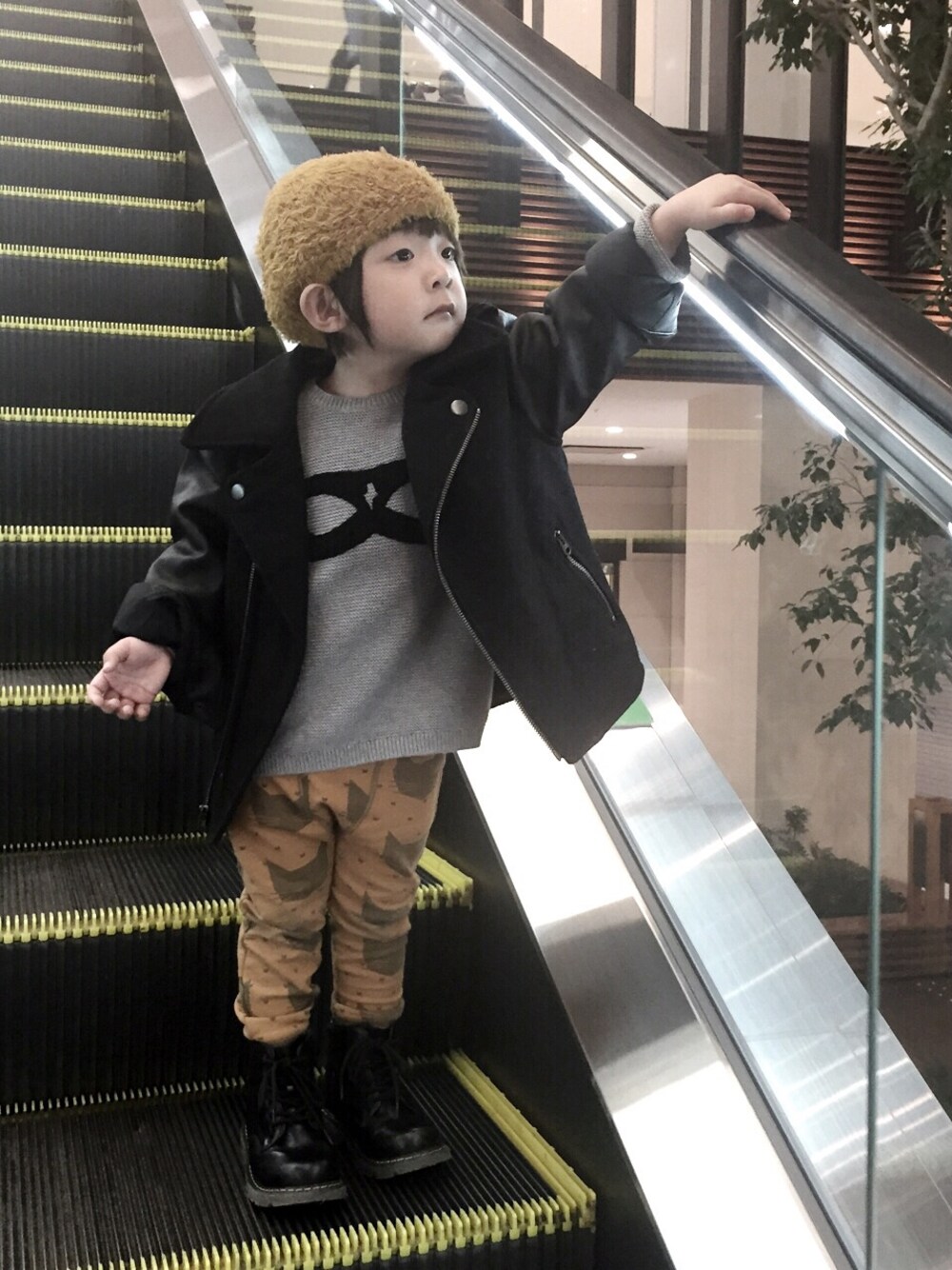 ブラック系のライダースジャケット、グレー系のニット/セーター、イエロー系のその他パンツを着用したキッズの春コーディネートの1枚目の写真