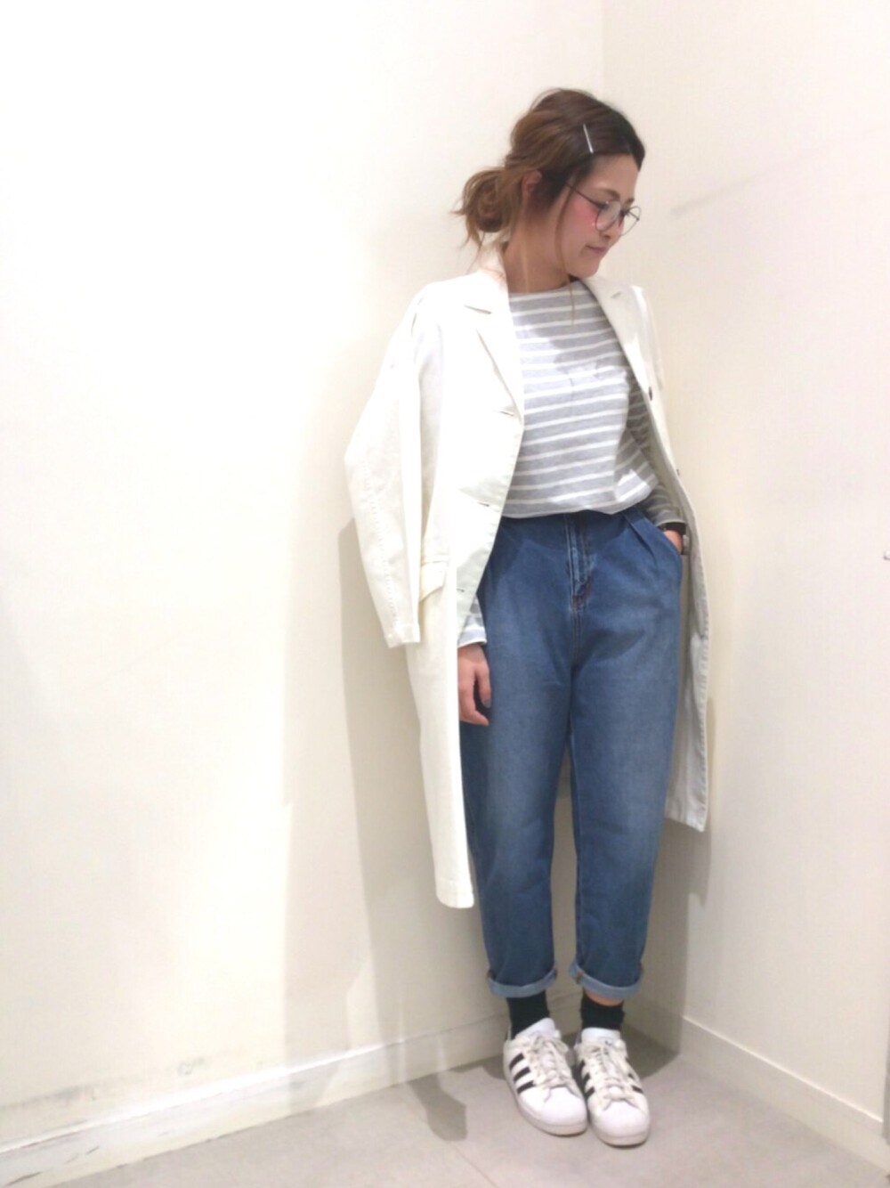 ホワイト系のチェスターコート、ブルー系のデニムパンツ、グレー系のTシャツ/カットソーを着用したレディースの冬コーディネートの1枚目の写真