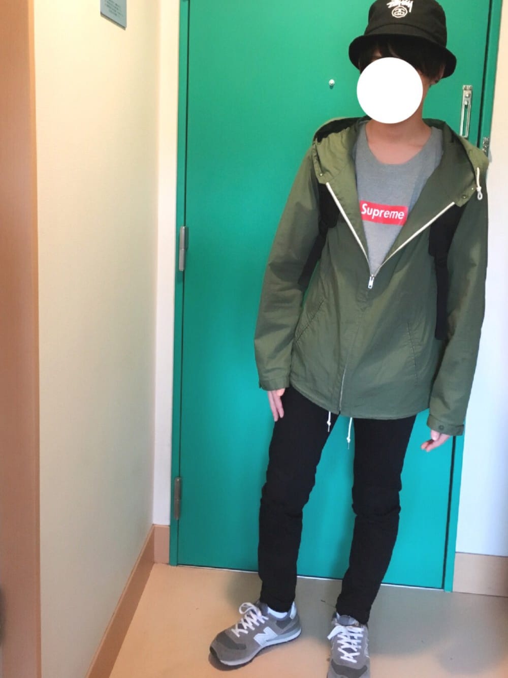 グリーン系のマウンテンパーカー、グレー系のTシャツ/カットソー、ブラック系のデニムパンツを着用したメンズの春コーディネートの1枚目の写真