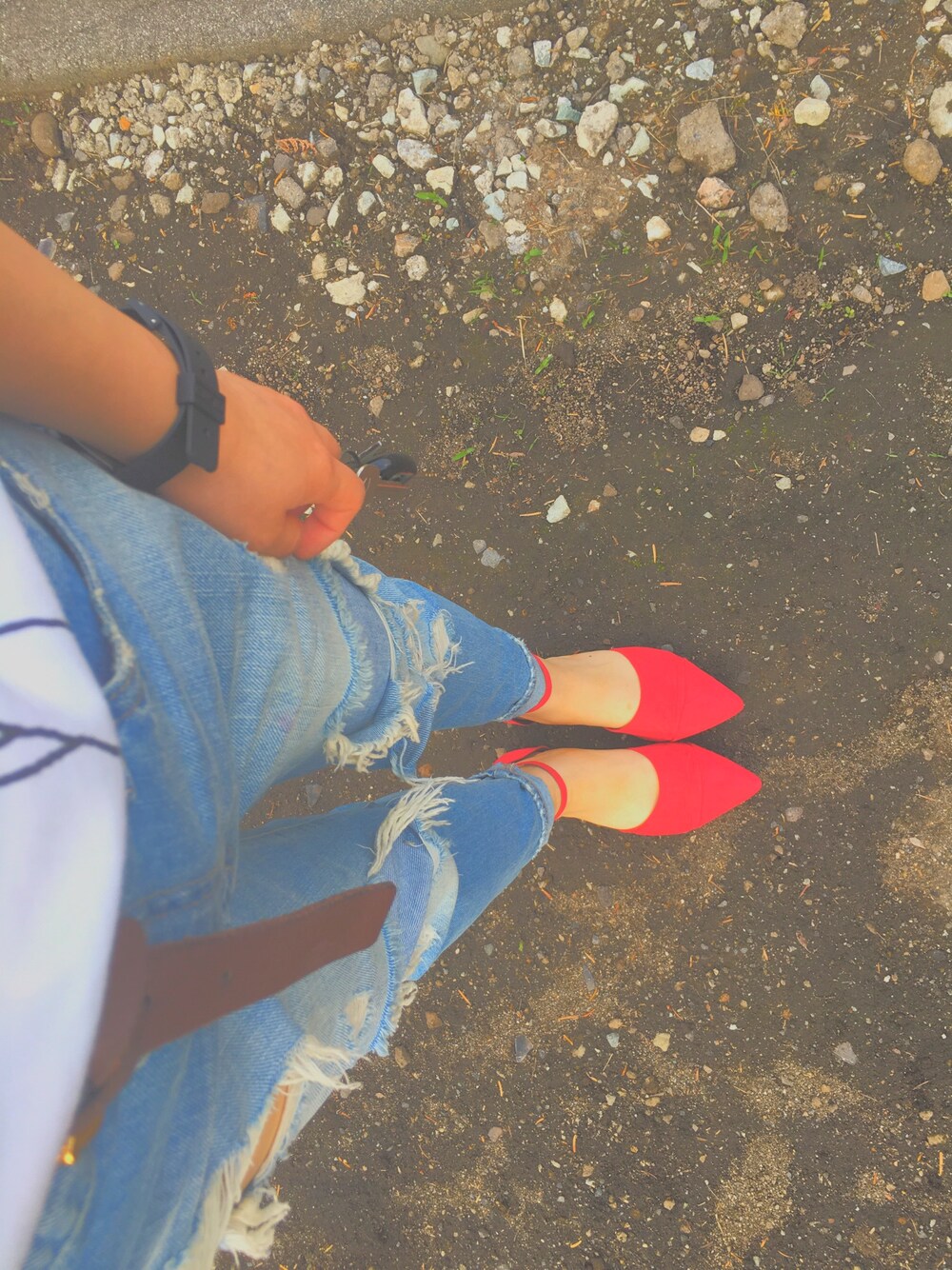 レッド系のパンプス、ブルー系のデニムパンツ、ブラック系のアナログ腕時計を着用したレディースの秋コーディネートの1枚目の写真