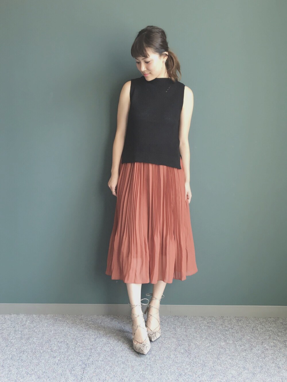 ブラック系のニット/セーター、その他のパンプス、オレンジ系のスカートを着用したレディースの夏コーディネートの1枚目の写真