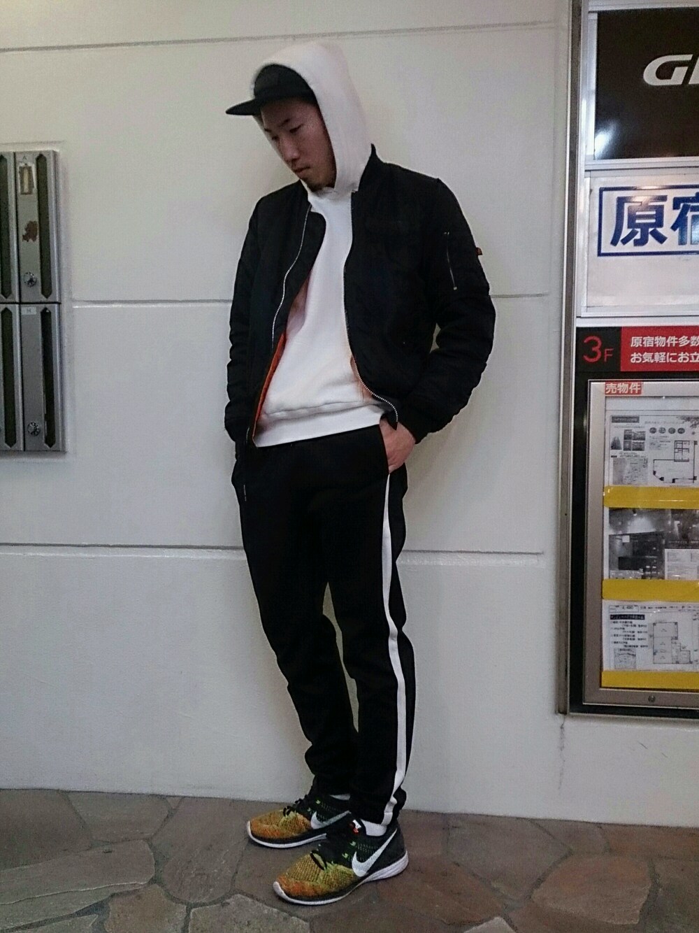 「UPSTART×BURKS.BULL、MA-1、モノトーン、Champion、イージーパンツ、NIKE、FLYKNIT、ジェットキャップ、プルオーバーパーカー、原宿」｜「UP STARTの脇ラインジャージパンツ（その他パンツ、ブラック系）」を使った、TOMOYAさん（メンズ・174cm）の春コーディネートの1枚目の写真
