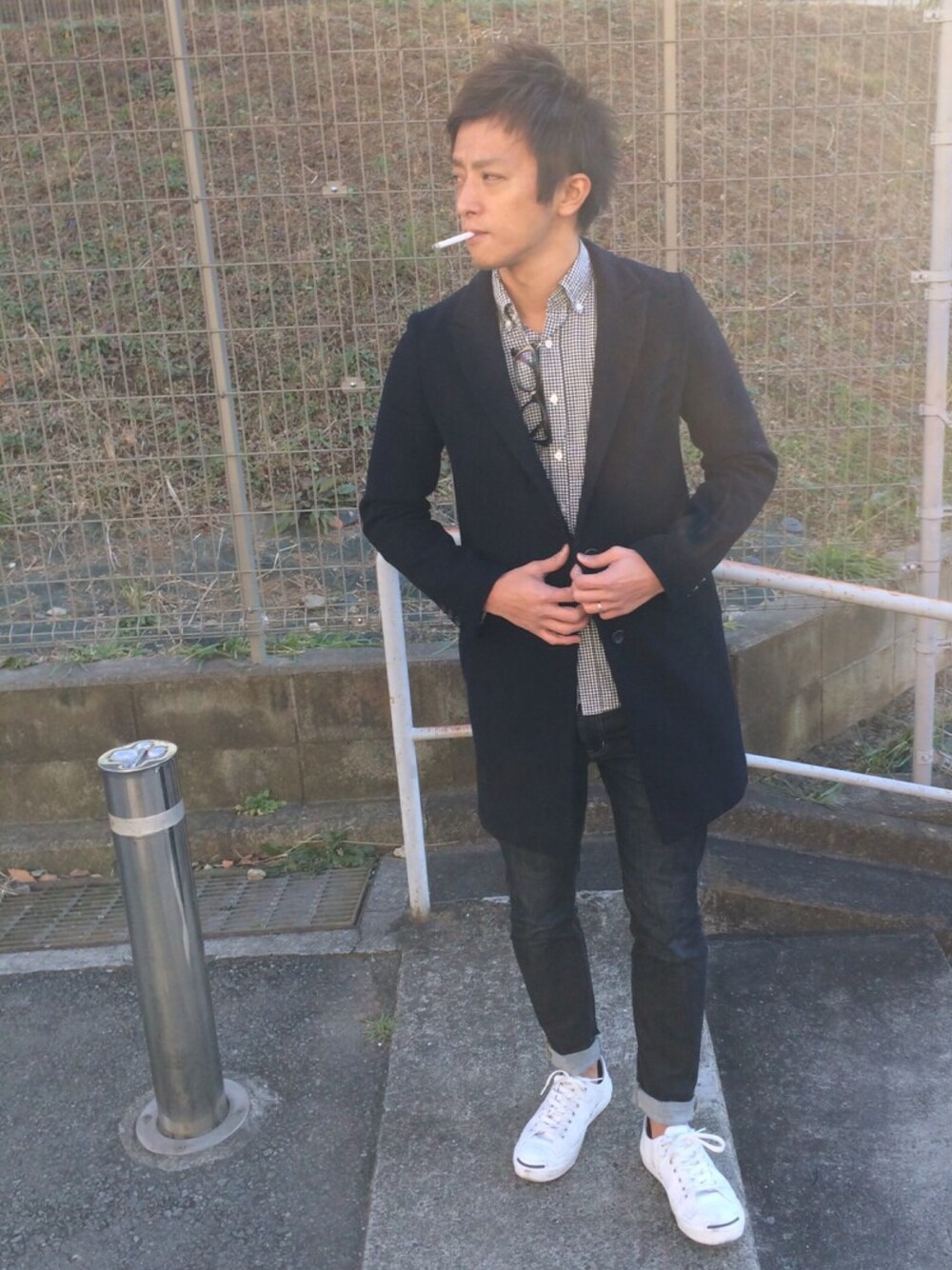 ブラック系のシャツ/ブラウス、ブラック系のチェスターコート、ブルー系のデニムパンツを着用したメンズの冬コーディネートの1枚目の写真