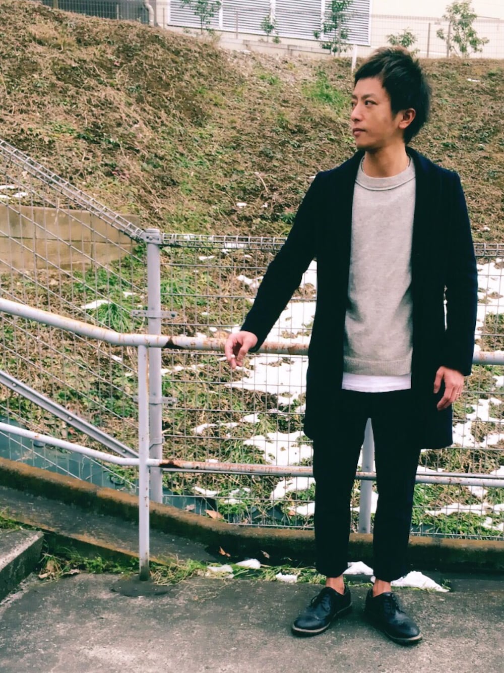 ベージュ系のニット/セーター、ブラック系のチェスターコート、ホワイト系のTシャツ/カットソーを着用したメンズの冬コーディネートの1枚目の写真