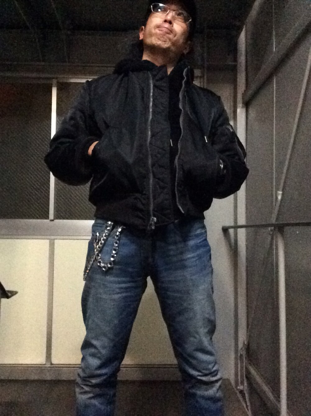 ブラック系のパーカー、ブルー系のデニムパンツ、ブラック系のミリタリージャケットを着用したメンズの冬コーディネートの1枚目の写真