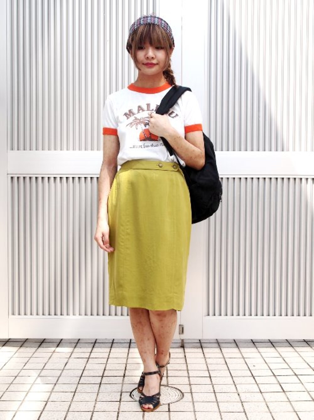 ホワイト系のTシャツ/カットソー、イエロー系のスカート、ブラック系のバックパック/リュックを着用したレディースの夏コーディネートの1枚目の写真