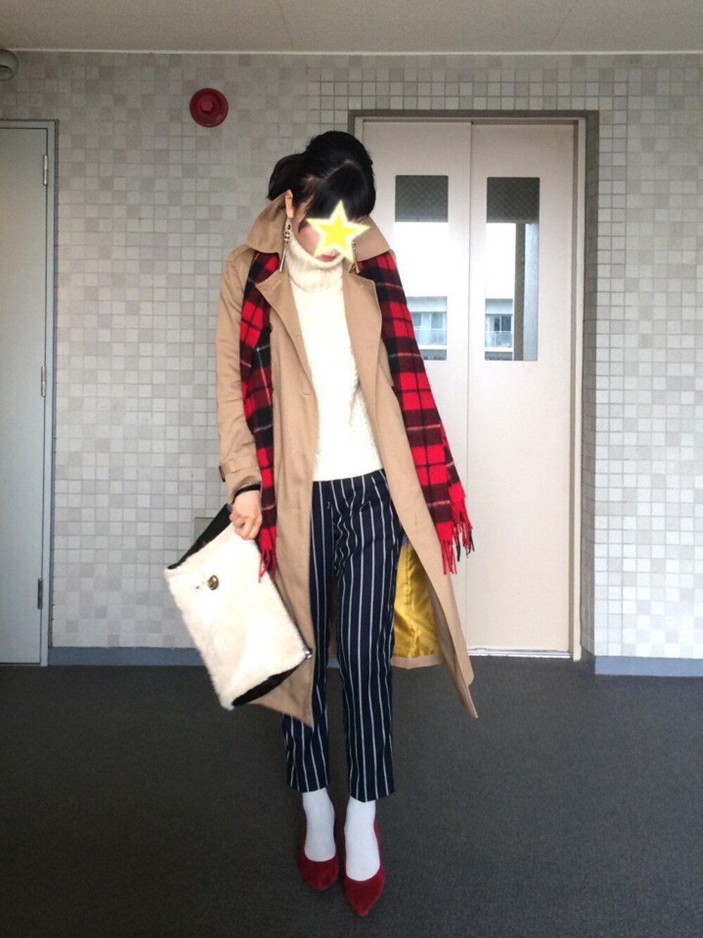 ベージュ系のクラッチバッグ、ベージュ系のトレンチコート、ホワイト系のチャームを着用したレディースの冬コーディネートの1枚目の写真