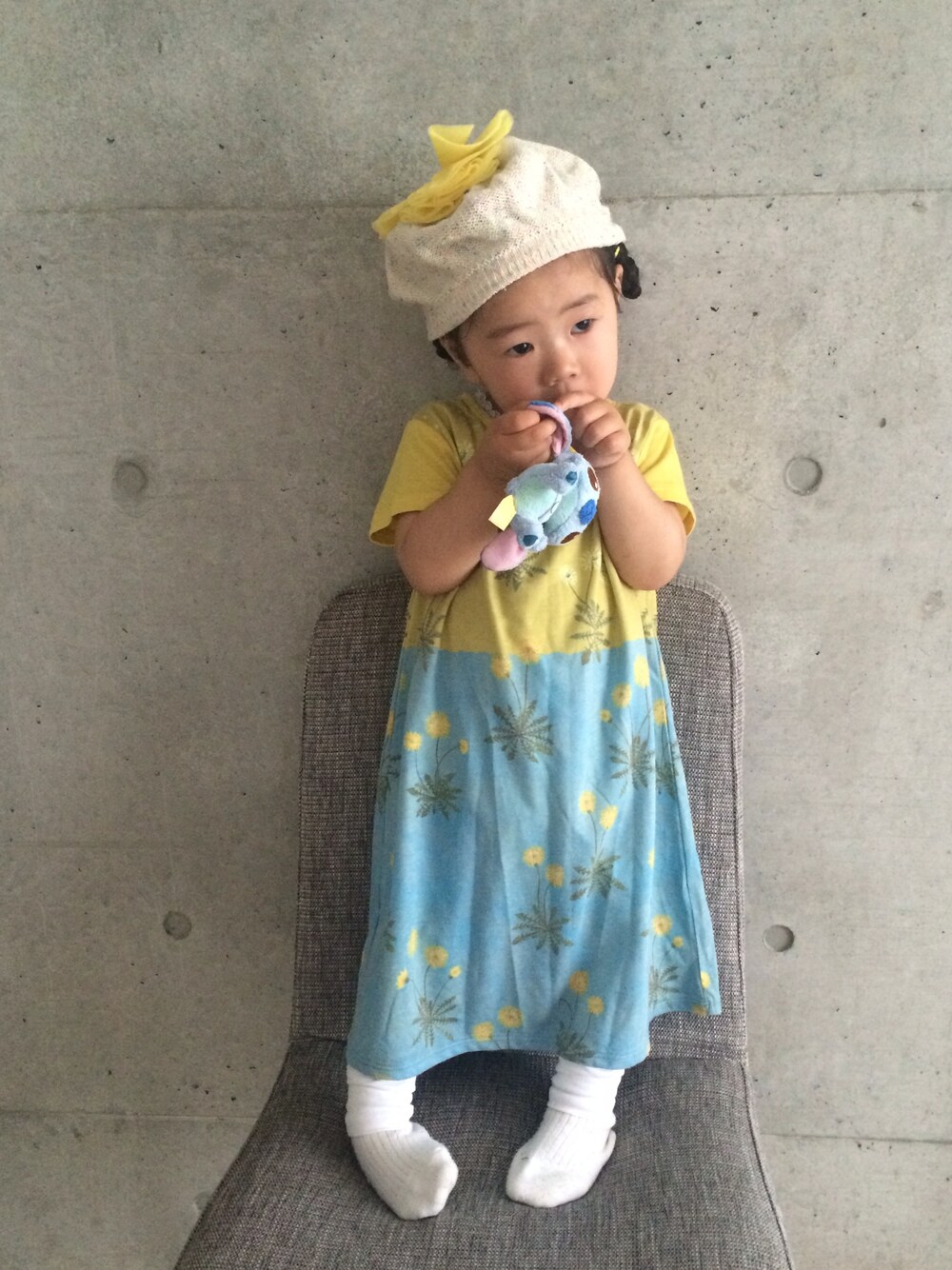 イエロー系のワンピース、ホワイト系のレギンス/スパッツ、ホワイト系のソックス/靴下を着用したキッズの春コーディネートの1枚目の写真