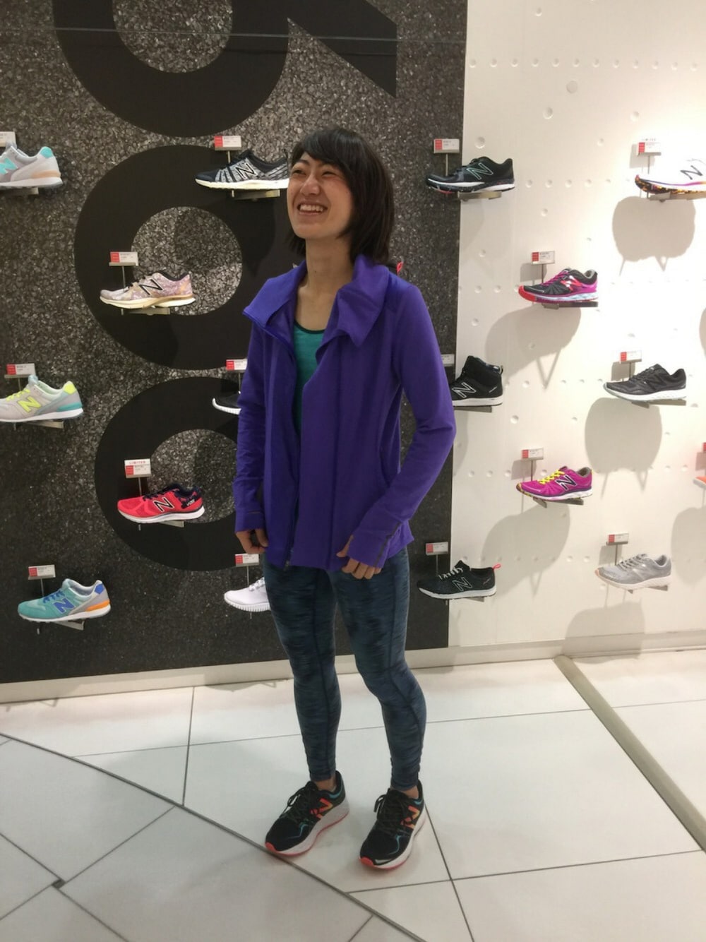 グリーン系のタンクトップ、パープル系のブルゾン、ブラック系のシューズを着用したレディースの秋コーディネートの1枚目の写真