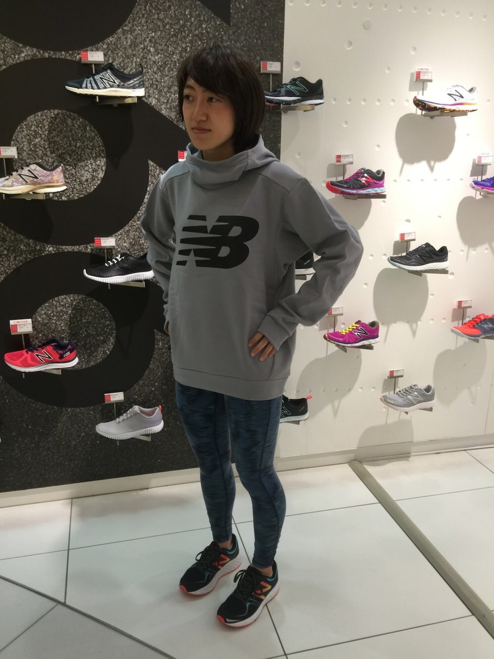 グレー系のパーカー、ブラック系のシューズ、ブルー系のレギンス/スパッツを着用したレディースの秋コーディネートの1枚目の写真