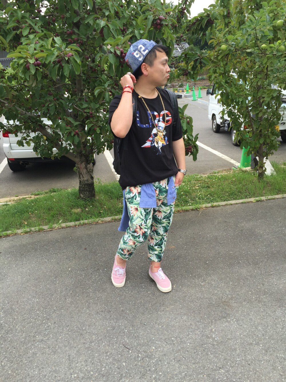 「ボタニカル柄、キャップ、Tシャツ、腰巻きスタイル、ネックレス、スニーカー、リュック」｜「LRGのアイテム（Tシャツ/カットソー、ブラック系）」を使った、小林一寿さん（メンズ・164cm）の夏コーディネートの1枚目の写真
