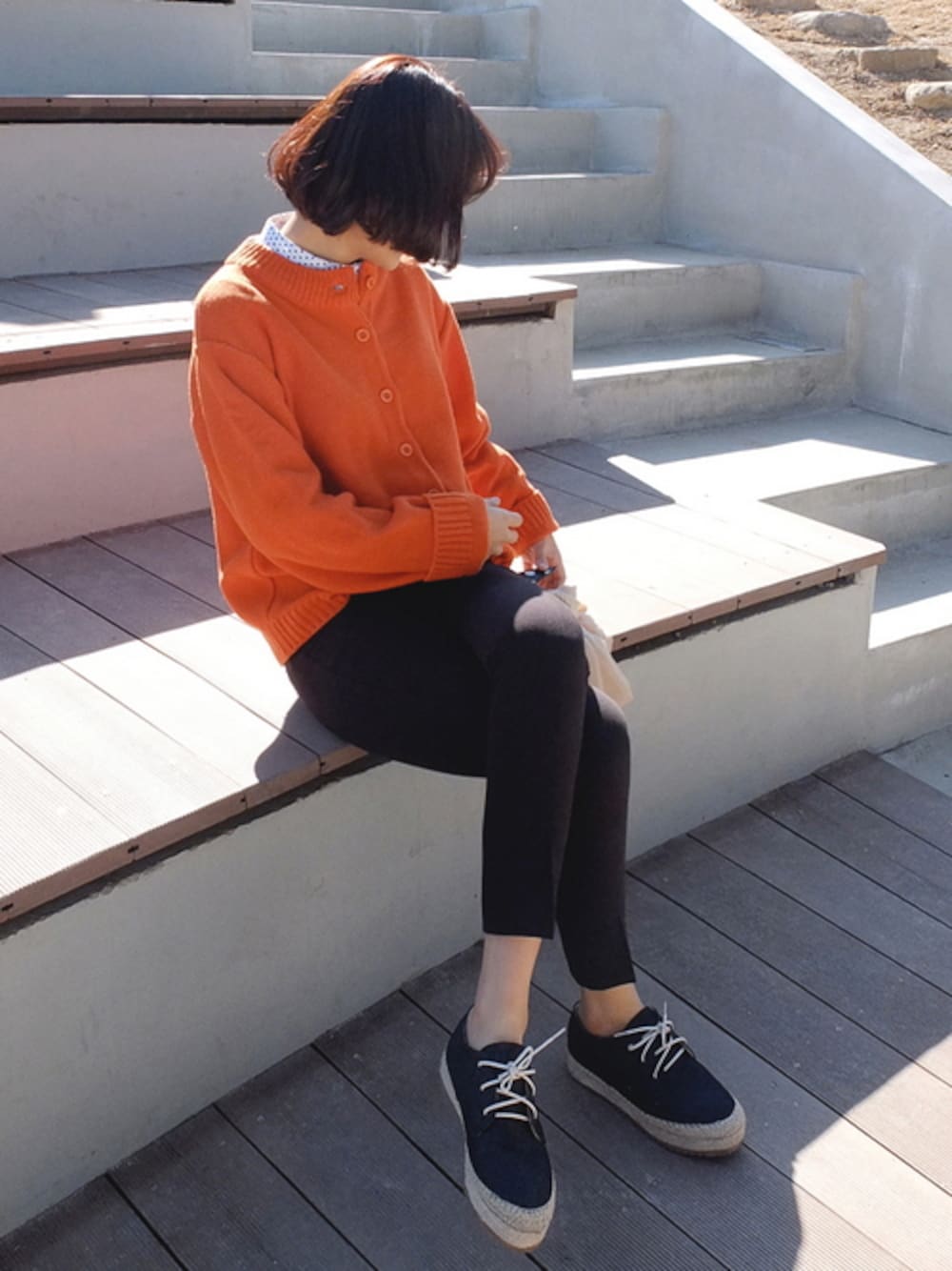 オレンジ系のカーディガン/ボレロを着用したレディースの冬コーディネートの1枚目の写真