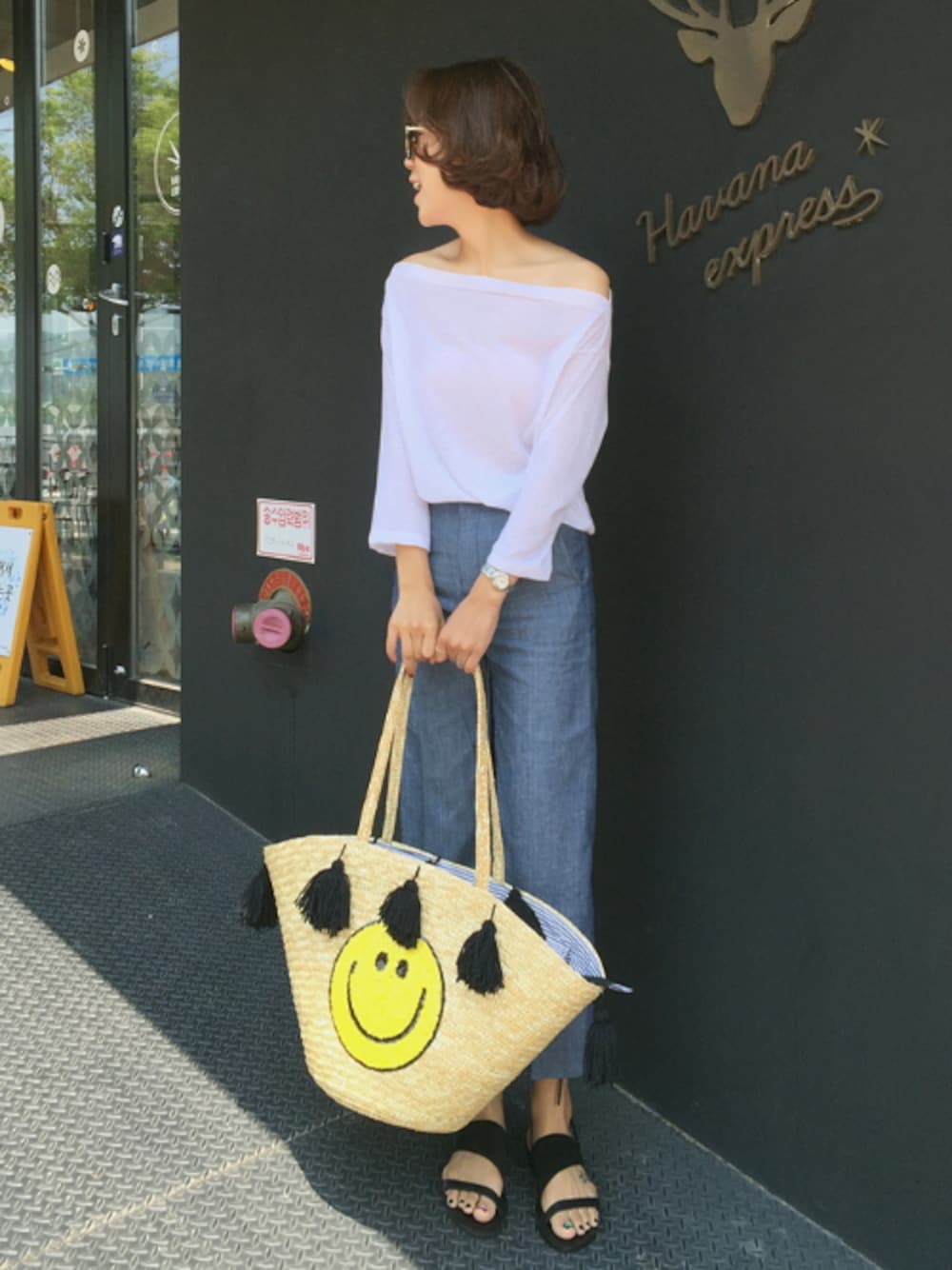 ホワイト系のTシャツ/カットソー、ブラック系のサンダル、ベージュ系のトートバッグを着用したレディースの夏コーディネートの1枚目の写真
