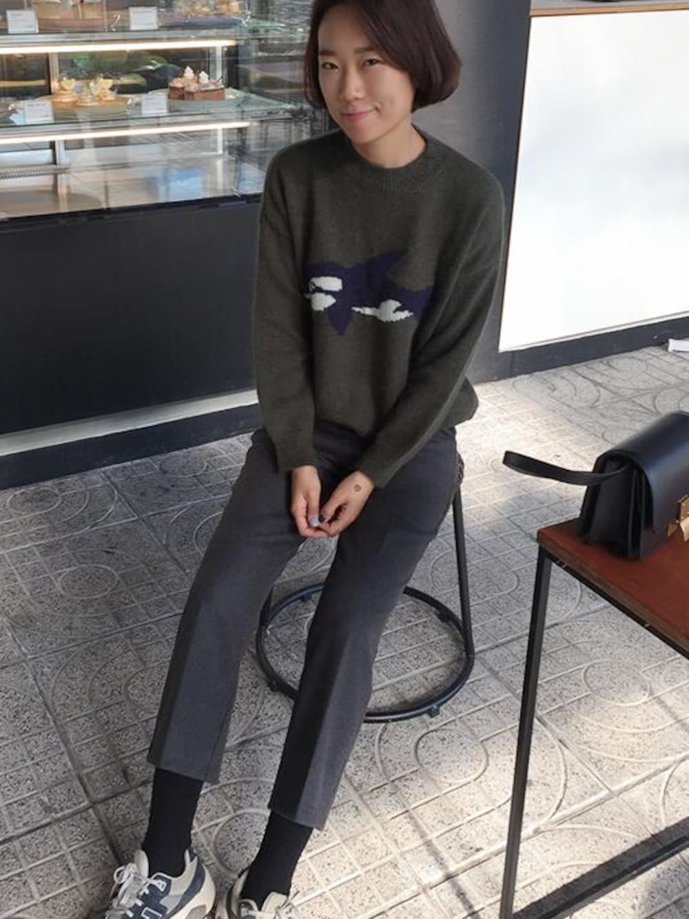 ブラック系のスラックス、グリーン系のニット/セーターを着用したレディースの冬コーディネートの1枚目の写真