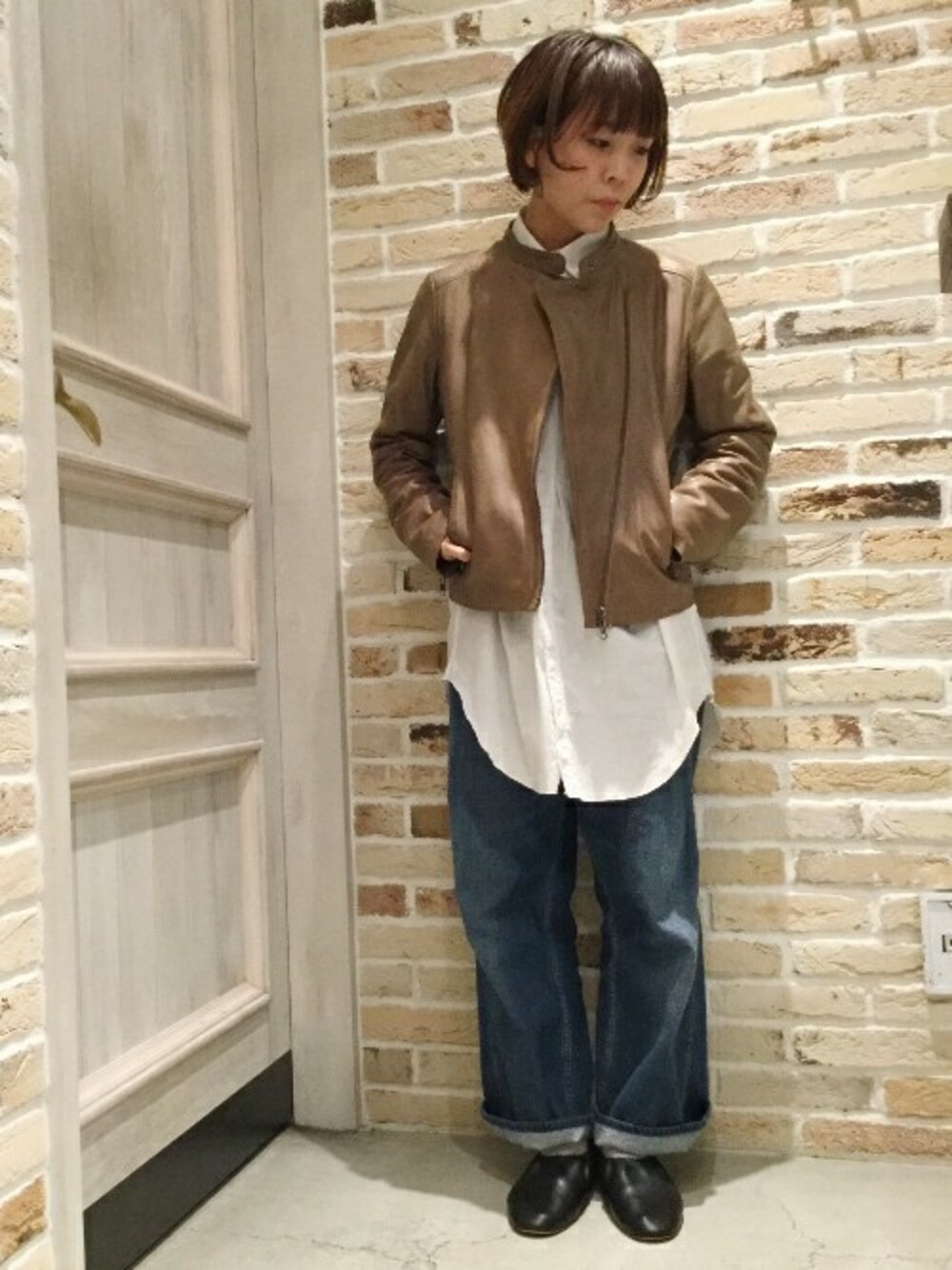 ベージュ系のライダースジャケットを着用したレディースの冬コーディネートの1枚目の写真