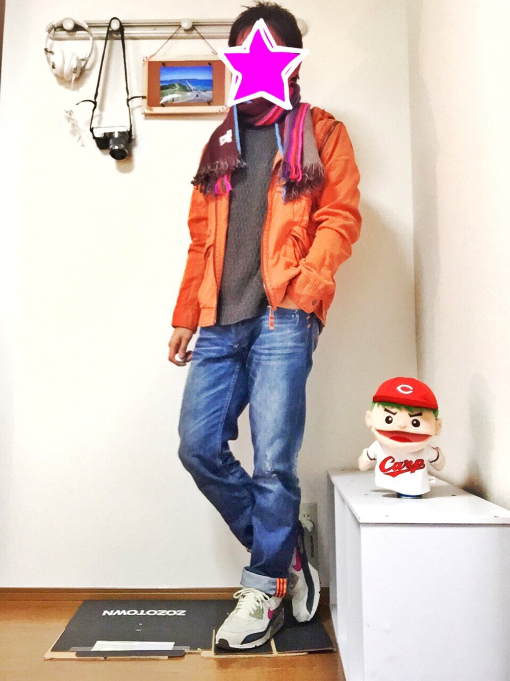 オレンジ系のミリタリージャケット、ブルー系のデニムパンツ、ホワイト系のスニーカーを着用したメンズの秋コーディネートの1枚目の写真