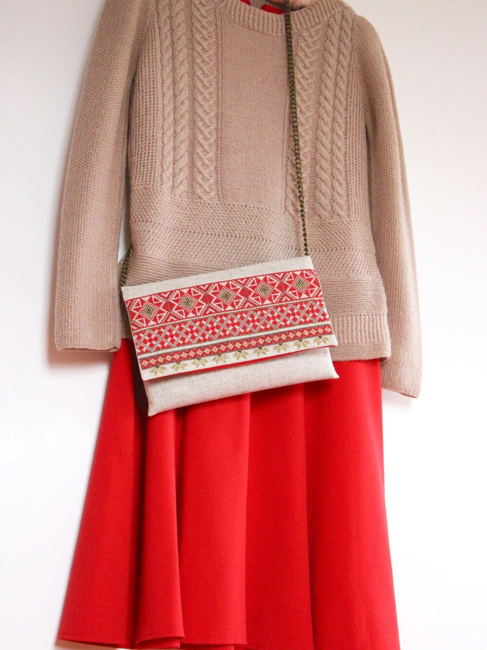 ベージュ系のニット/セーター、その他のクラッチバッグ、レッド系のワンピースを着用したレディースの秋コーディネートの1枚目の写真