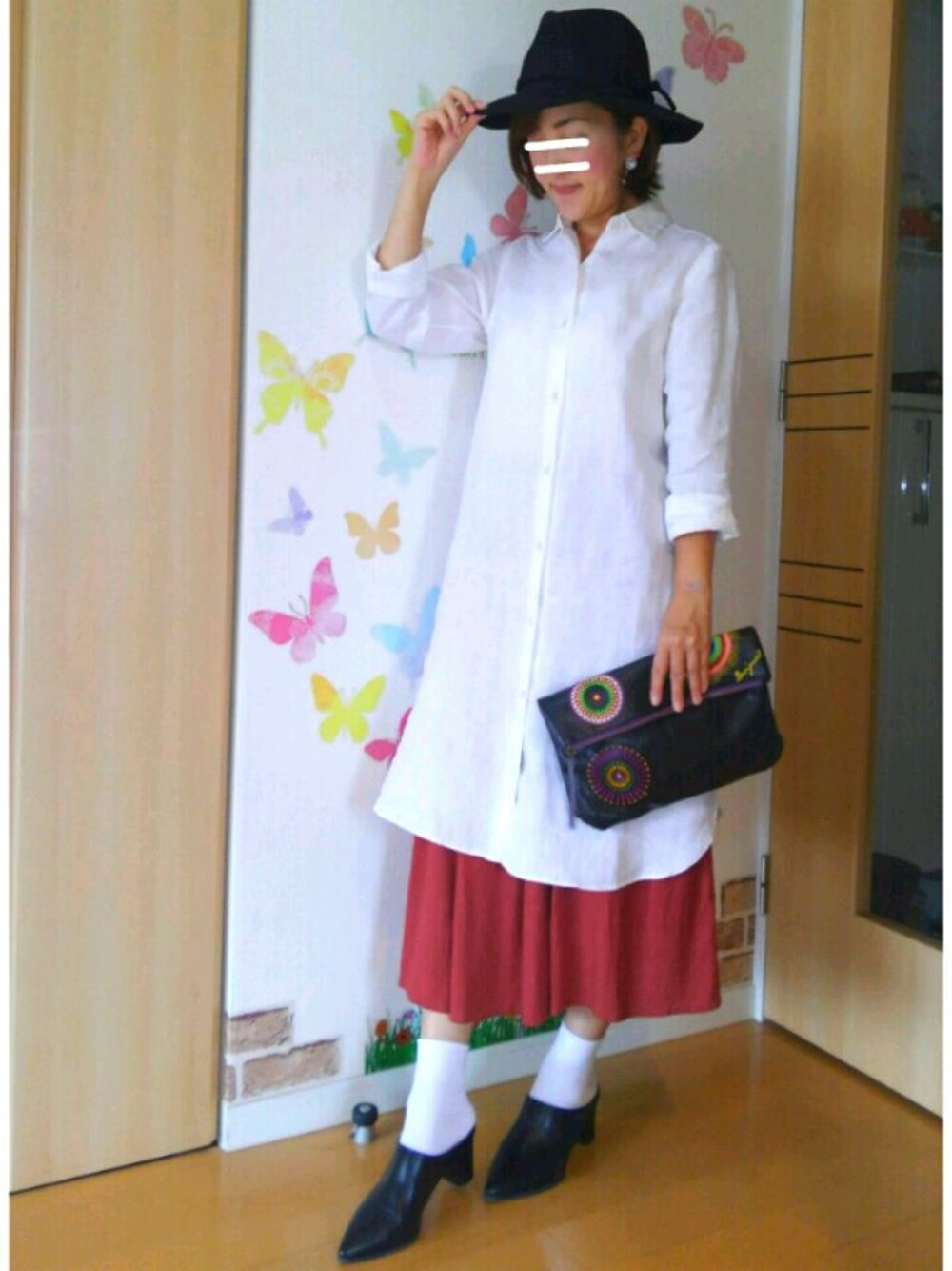 オレンジ系のスカート、ホワイト系のシャツワンピース、ブラック系のシューズを着用したレディースの秋コーディネートの1枚目の写真