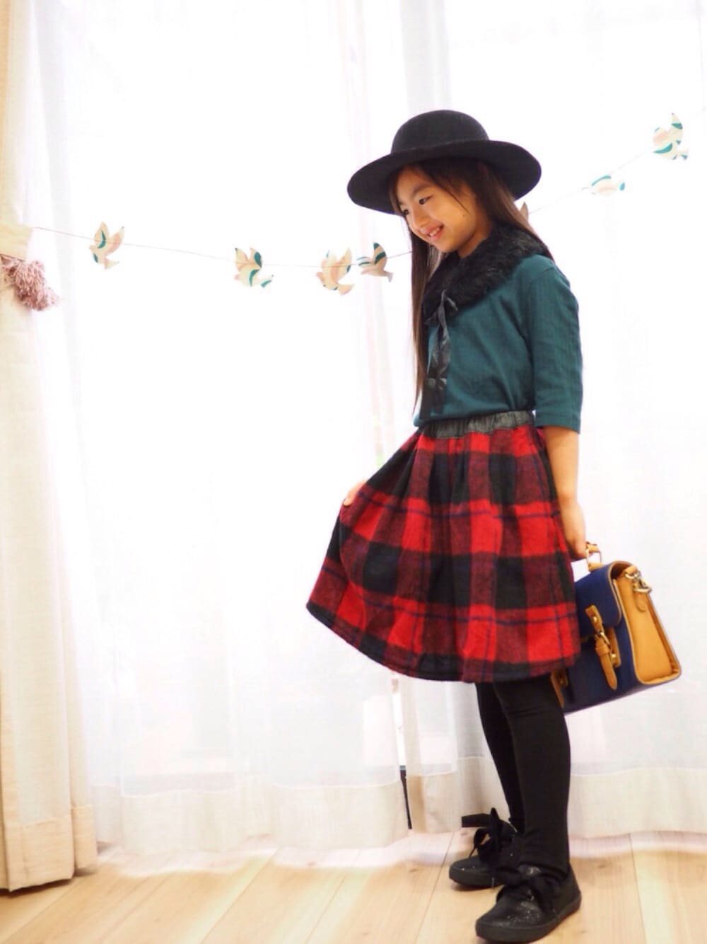 レッド系のスカート、ブラック系のスリッポン、グリーン系のTシャツ/カットソーを着用したキッズの秋コーディネートの1枚目の写真