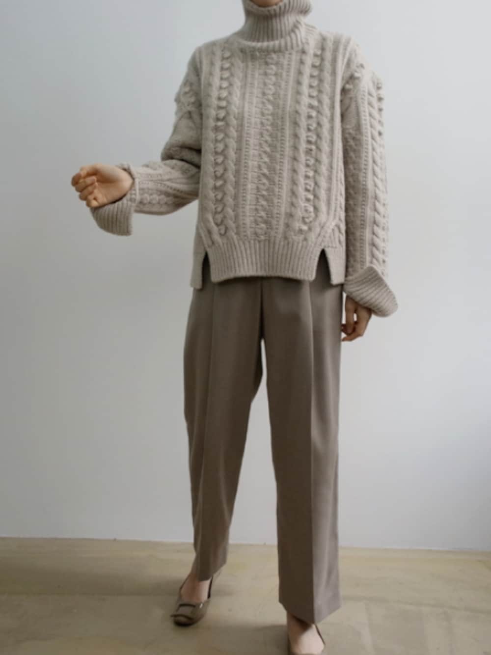 ベージュ系のニット/セーター、ブラウン系のスラックスを着用したレディースの冬コーディネートの1枚目の写真