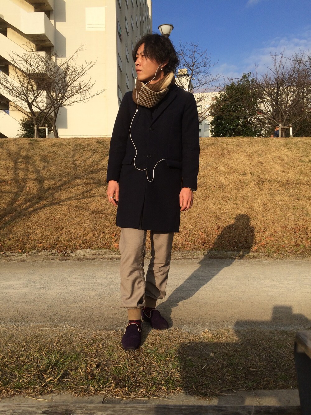 ブルー系のチェスターコート、ベージュ系のその他パンツ、パープル系のドレスシューズを着用したメンズの冬コーディネートの1枚目の写真