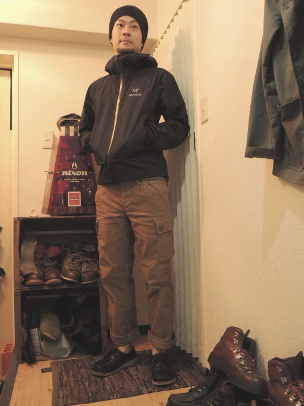 ブラック系のナイロンジャケット、ベージュ系のカーゴパンツ、ブラック系のモカシン/デッキシューズを着用したメンズの春コーディネートの1枚目の写真