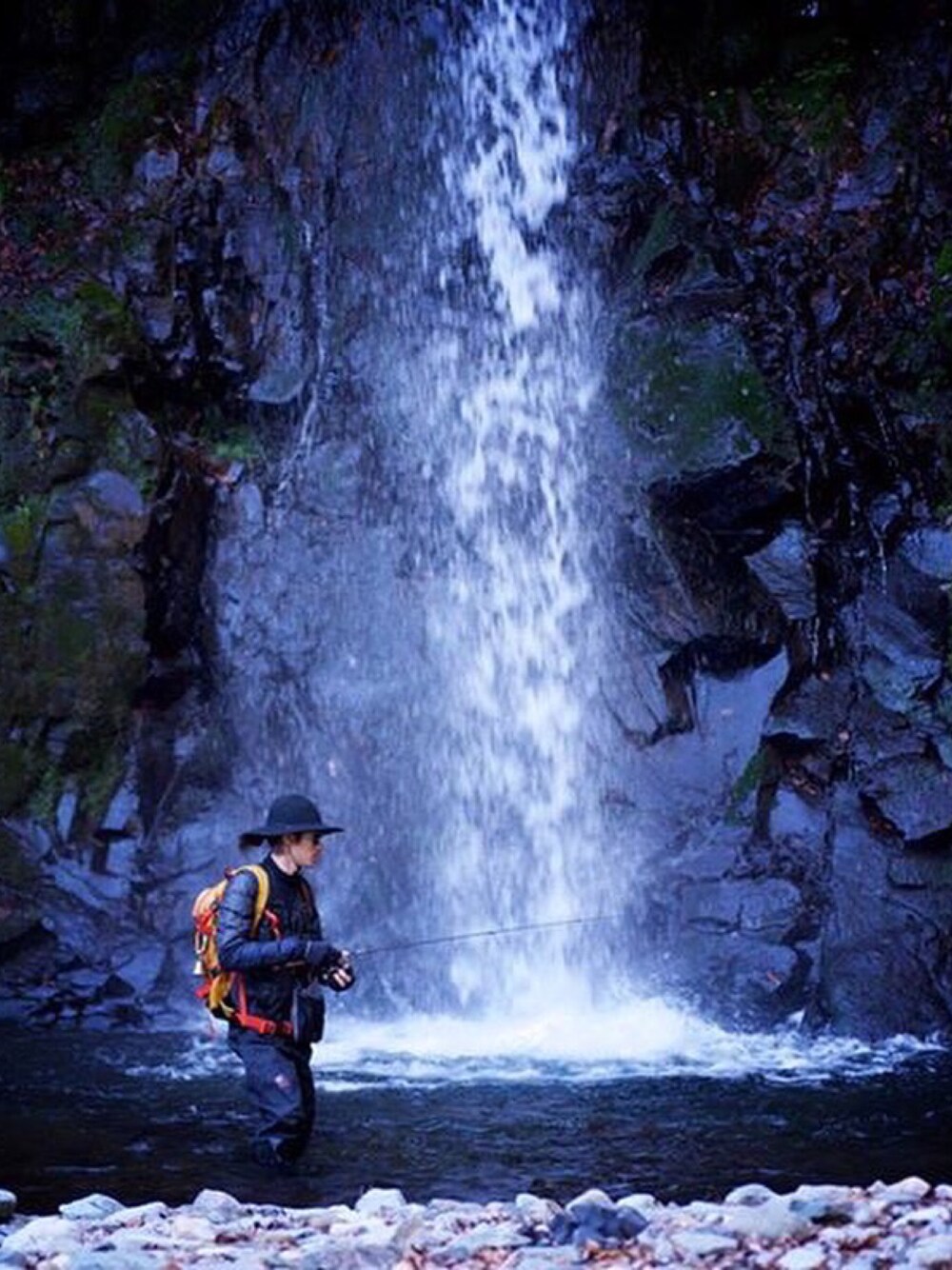 ブルー系のダウンジャケット/コート、オレンジ系のバックパック/リュック、ホワイト系のTシャツ/カットソーを着用したメンズの春コーディネートの1枚目の写真