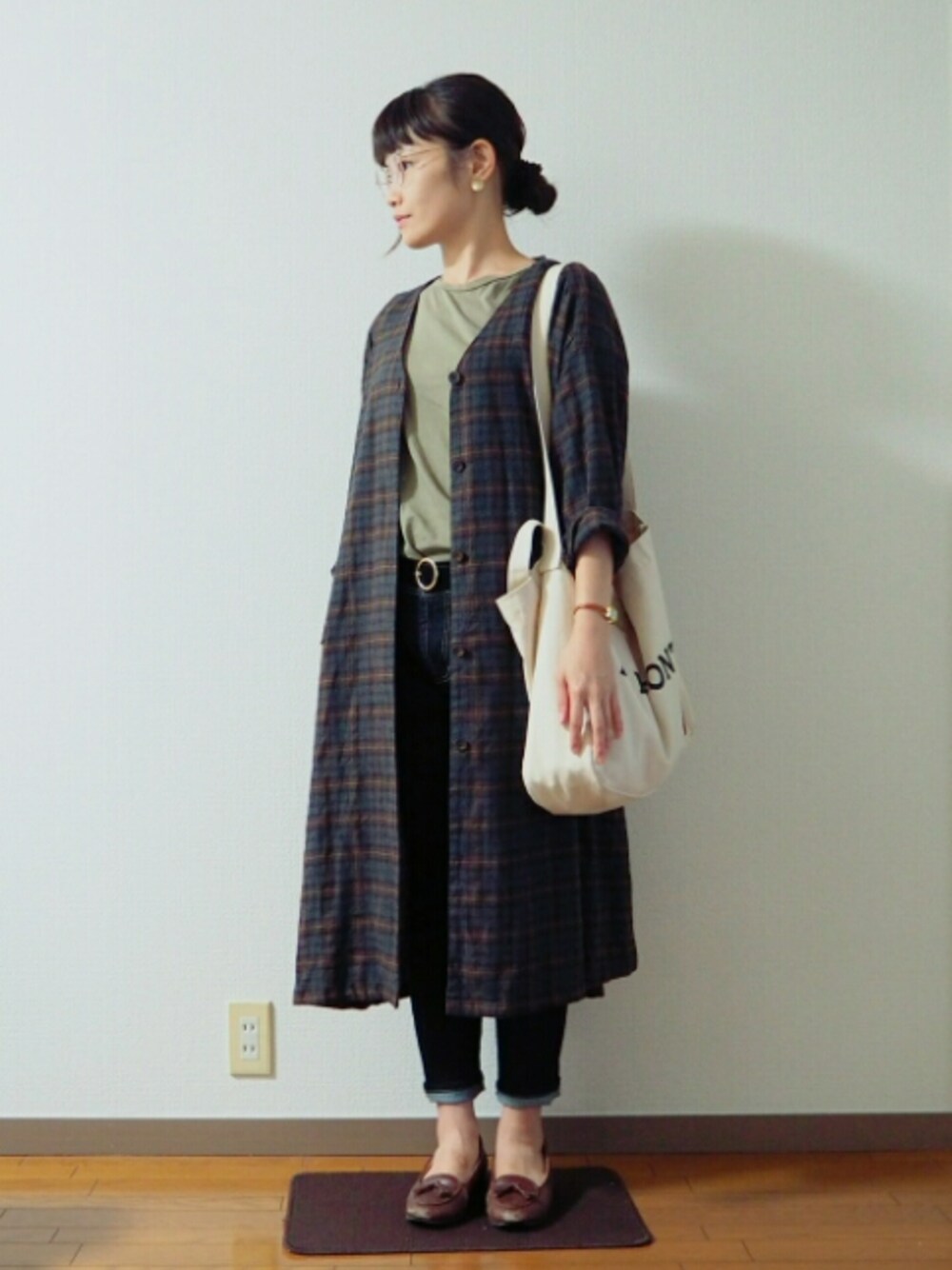 ブルー系のデニムパンツ、グリーン系のTシャツ/カットソー、ブラウン系のワンピースを着用したレディースの秋コーディネートの1枚目の写真