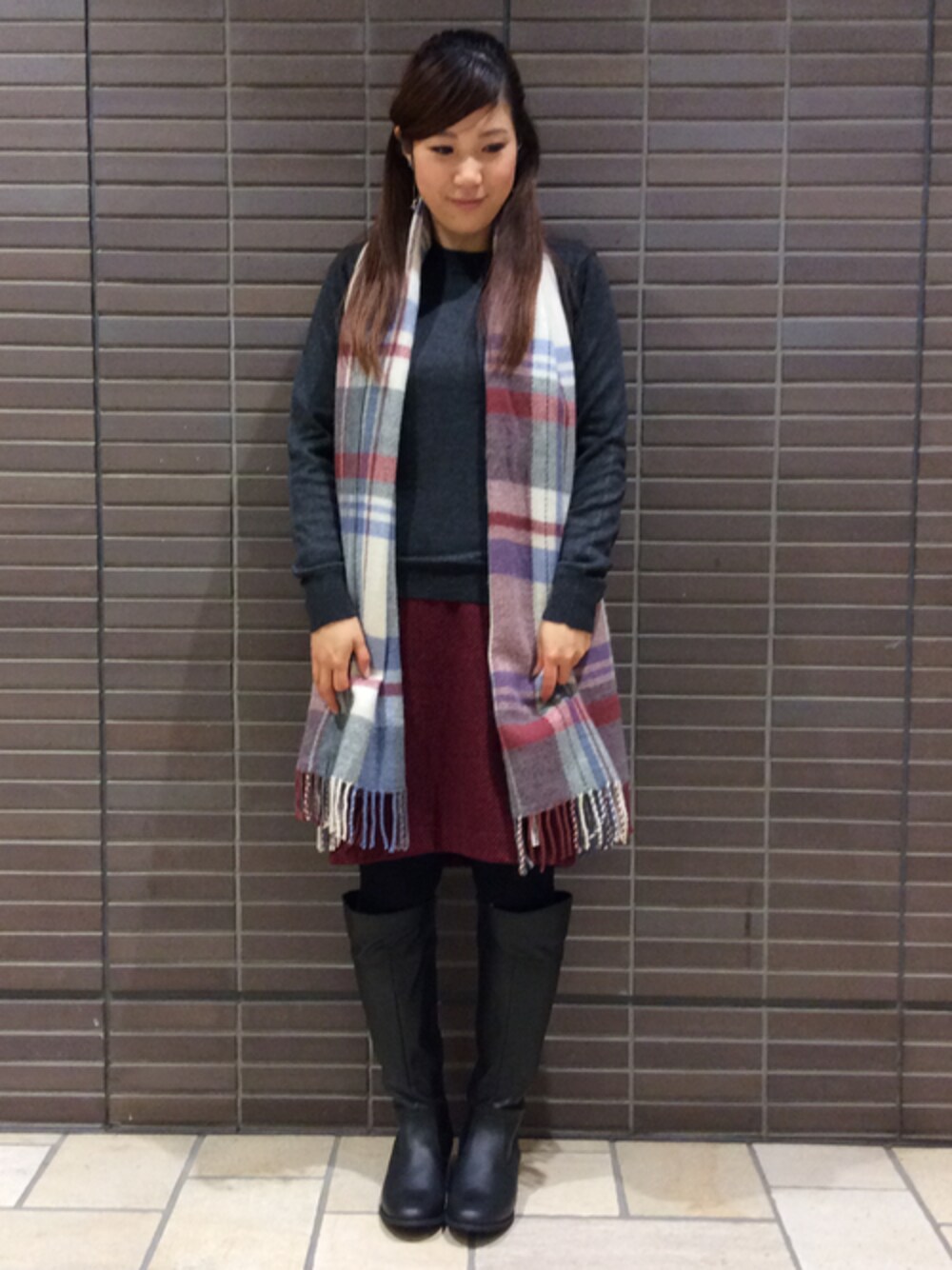 グレー系のニット/セーター、レッド系のスカート、ブラック系のブーツを着用したレディースの冬コーディネートの1枚目の写真