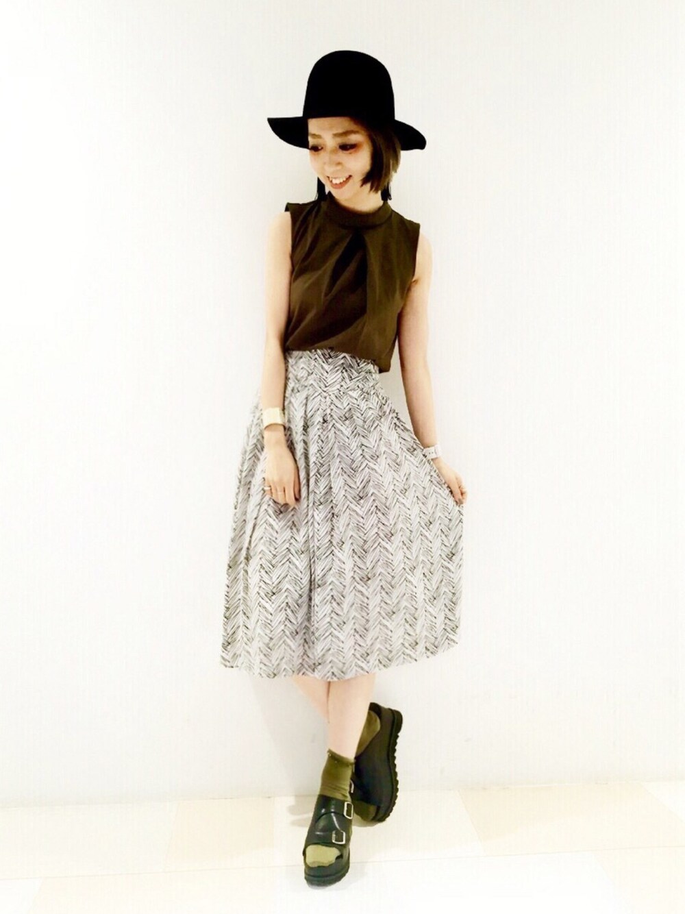 グリーン系のTシャツ/カットソー、グレー系のスカート、ブラック系のサンダルを着用したレディースの夏コーディネートの1枚目の写真