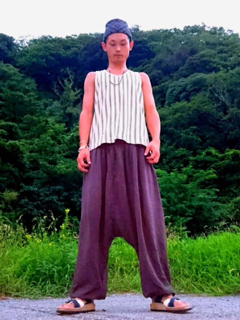 ベージュ系のタンクトップ、ブラウン系のその他パンツ、ブルー系のサンダルを着用したメンズの夏コーディネートの1枚目の写真