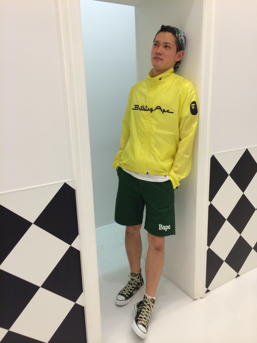 「ジャケット、ショートパンツ、ネオンカラー、A BATHING APE、ハイカットスニーカー、ジャケットスタイル、ジェットキャップ、スポーティ、蛍光色、ネオンイエロー」｜「A BATHING APEのNEON COLOR CYCLE JACKET（ナイロンジャケット、イエロー系）」を使った、児玉 洋介さん（メンズ・176cm）の夏コーディネートの1枚目の写真