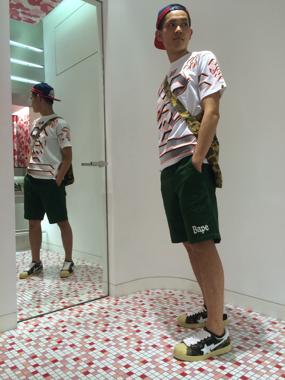 「カモフラ、キャップ、ショートパンツ、バッグ、ナンバリング、ショーツ、A BATHING APE、ローカットスニーカー、メッシュキャップ、白Tシャツ」｜「A BATHING APEのTEAM BAPE 88（Tシャツ/カットソー、ホワイト系）」を使った、児玉 洋介さん（メンズ・176cm）の夏コーディネートの1枚目の写真