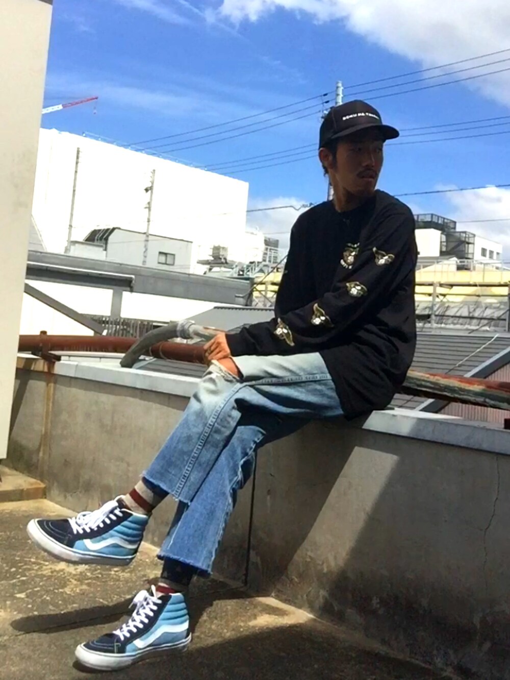ブラック系のTシャツ/カットソー、ブルー系のデニムパンツ、ブルー系のスニーカーを着用したメンズの秋コーディネートの1枚目の写真