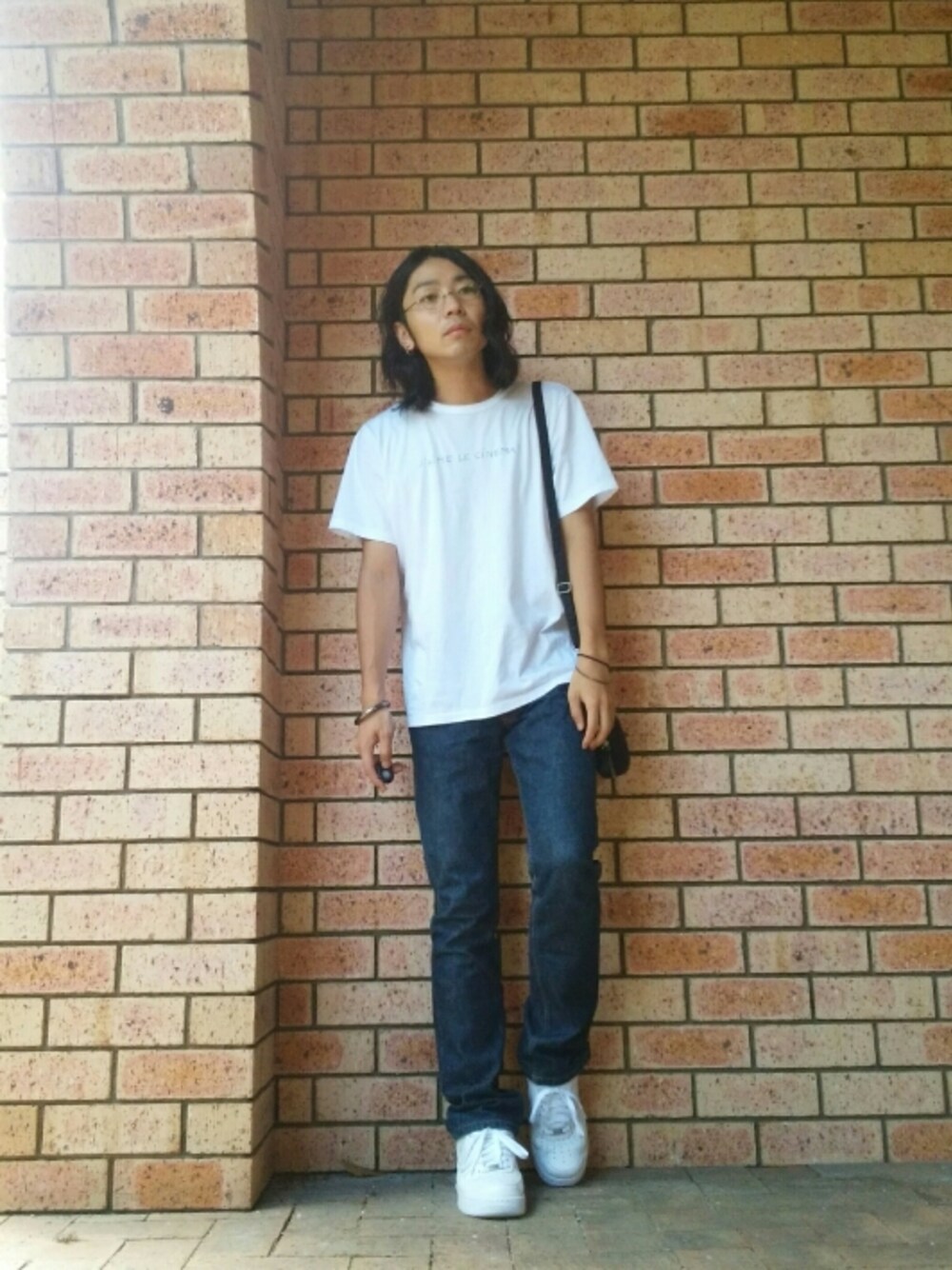 ブラック系のショルダーバッグ、ブルー系のデニムパンツ、ホワイト系のスニーカーを着用したメンズの秋コーディネートの1枚目の写真