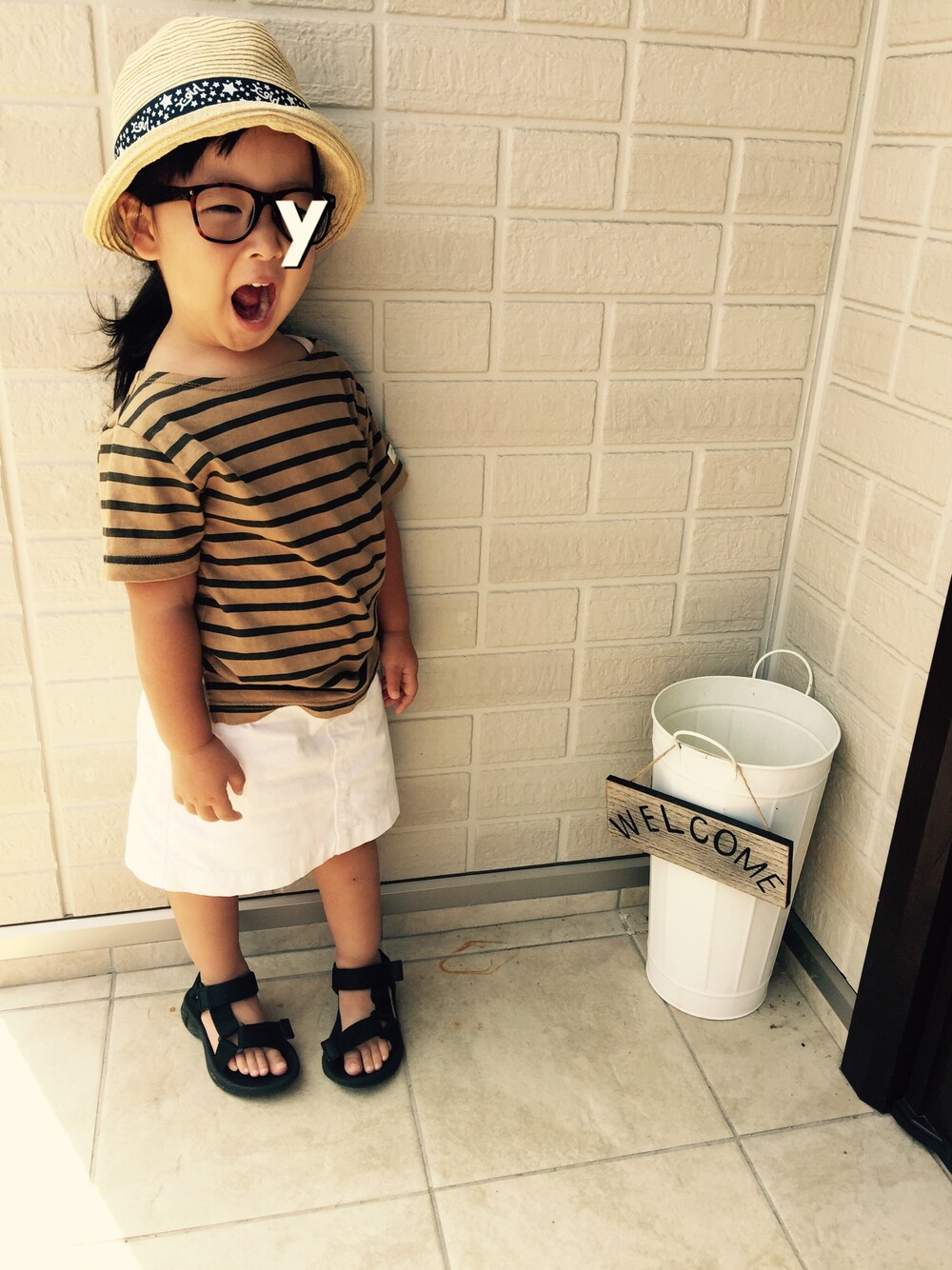レッド系のTシャツ/カットソー、ブラック系のサンダル、ベージュ系のハットを着用したキッズの夏コーディネートの1枚目の写真