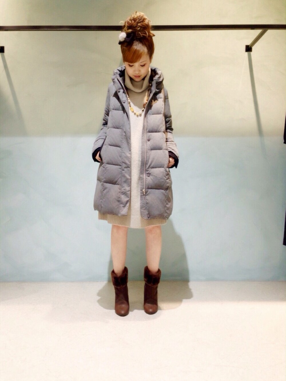 グレー系のダウンジャケット/コート、グレー系のワンピース、ブラウン系のブーツを着用したレディースの冬コーディネートの1枚目の写真