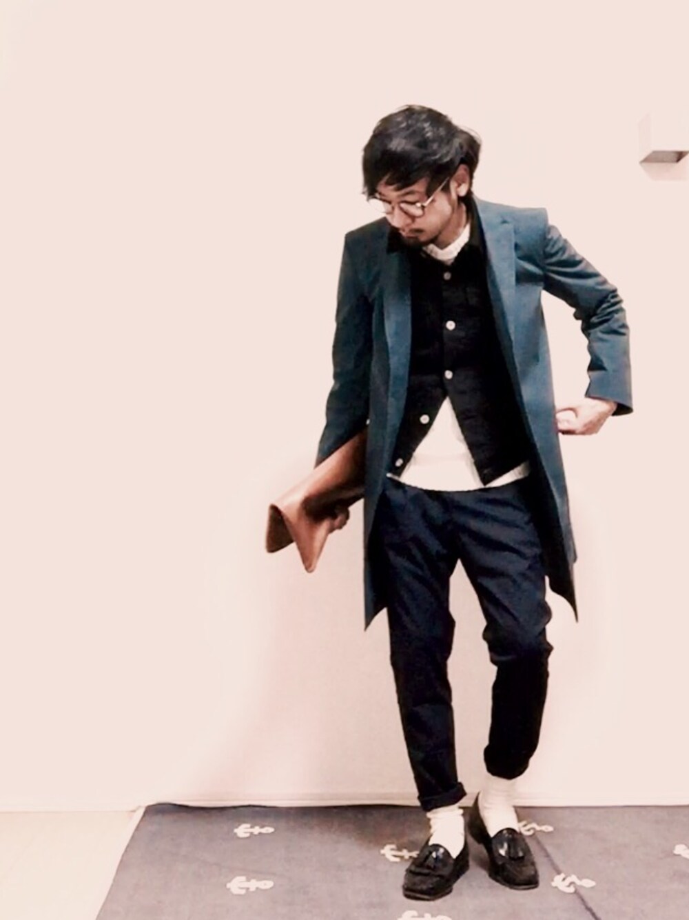 ホワイト系のニット/セーター、ブラック系のデニムジャケット、ブラウン系のクラッチバッグを着用したメンズの冬コーディネートの1枚目の写真