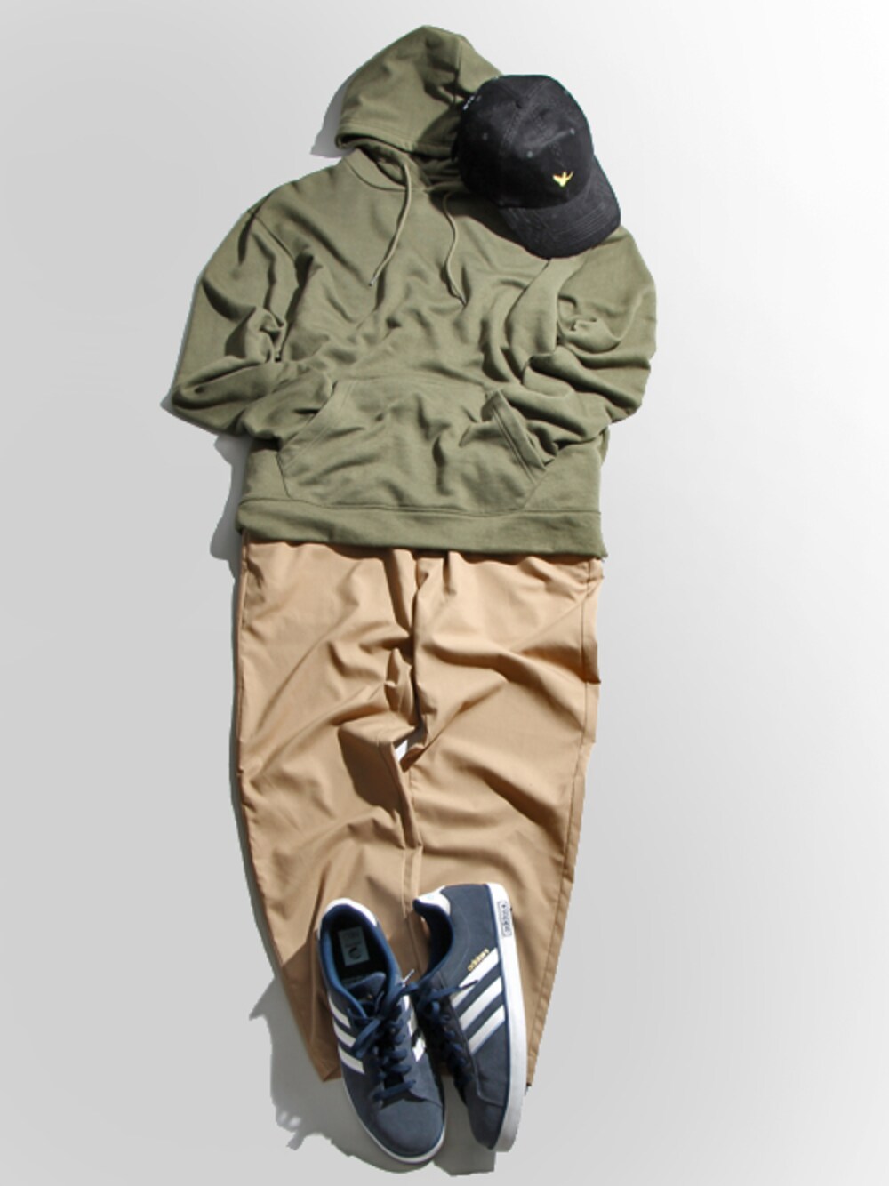 グリーン系のパーカー、ベージュ系のスラックス、ブルー系のスニーカーを着用したメンズの秋コーディネートの1枚目の写真