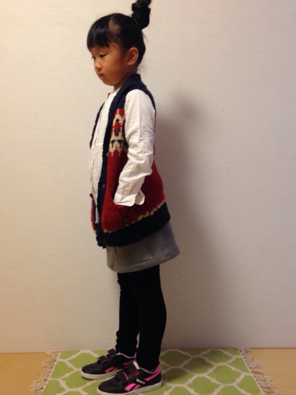 ホワイト系のシャツ/ブラウス、レッド系のニット/セーター、グレー系のスカートを着用したキッズの冬コーディネートの1枚目の写真